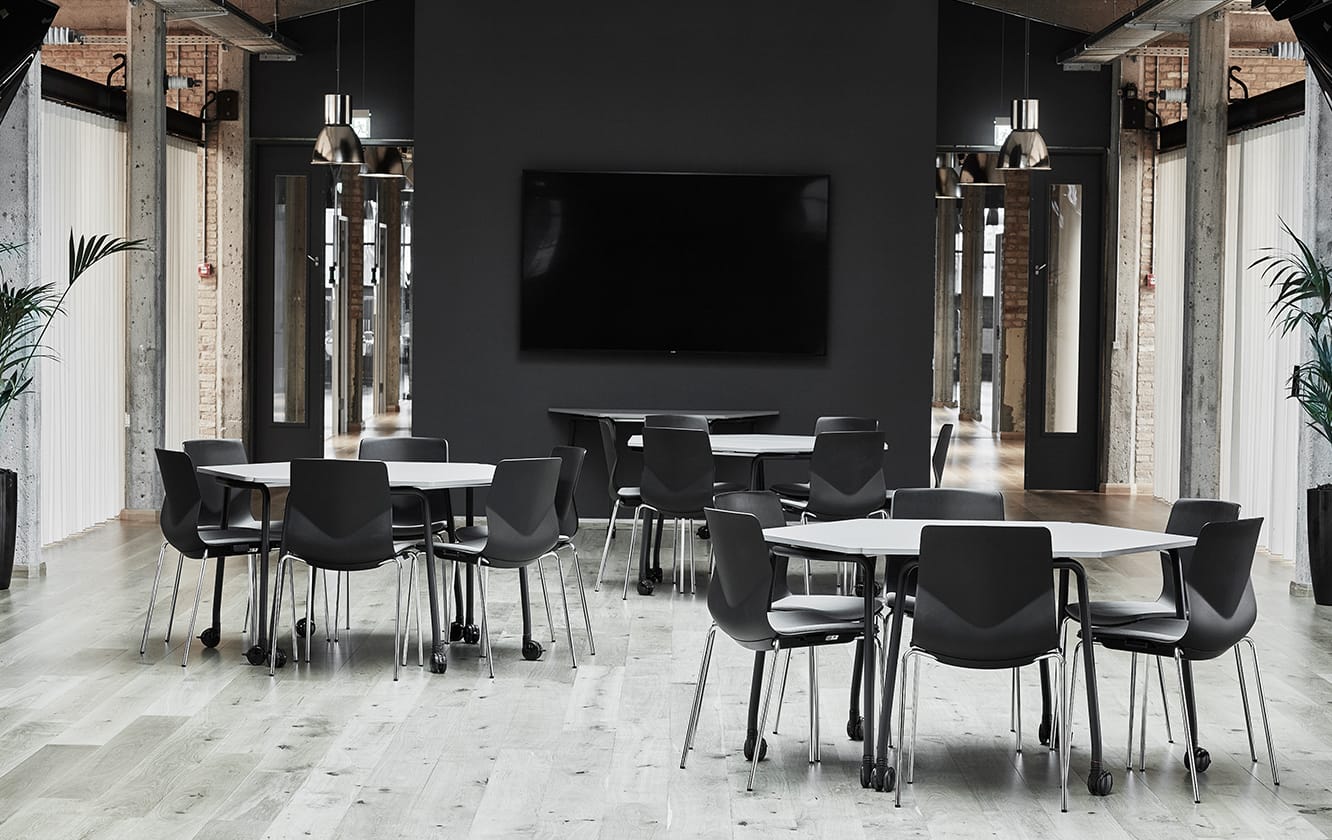 A black and white conference room with tables and office desk chairs.